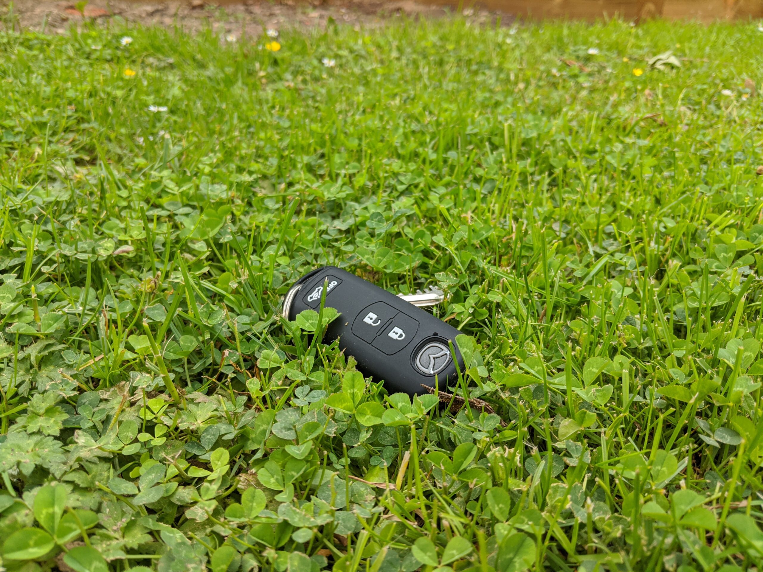 Mazda car key laying on grass